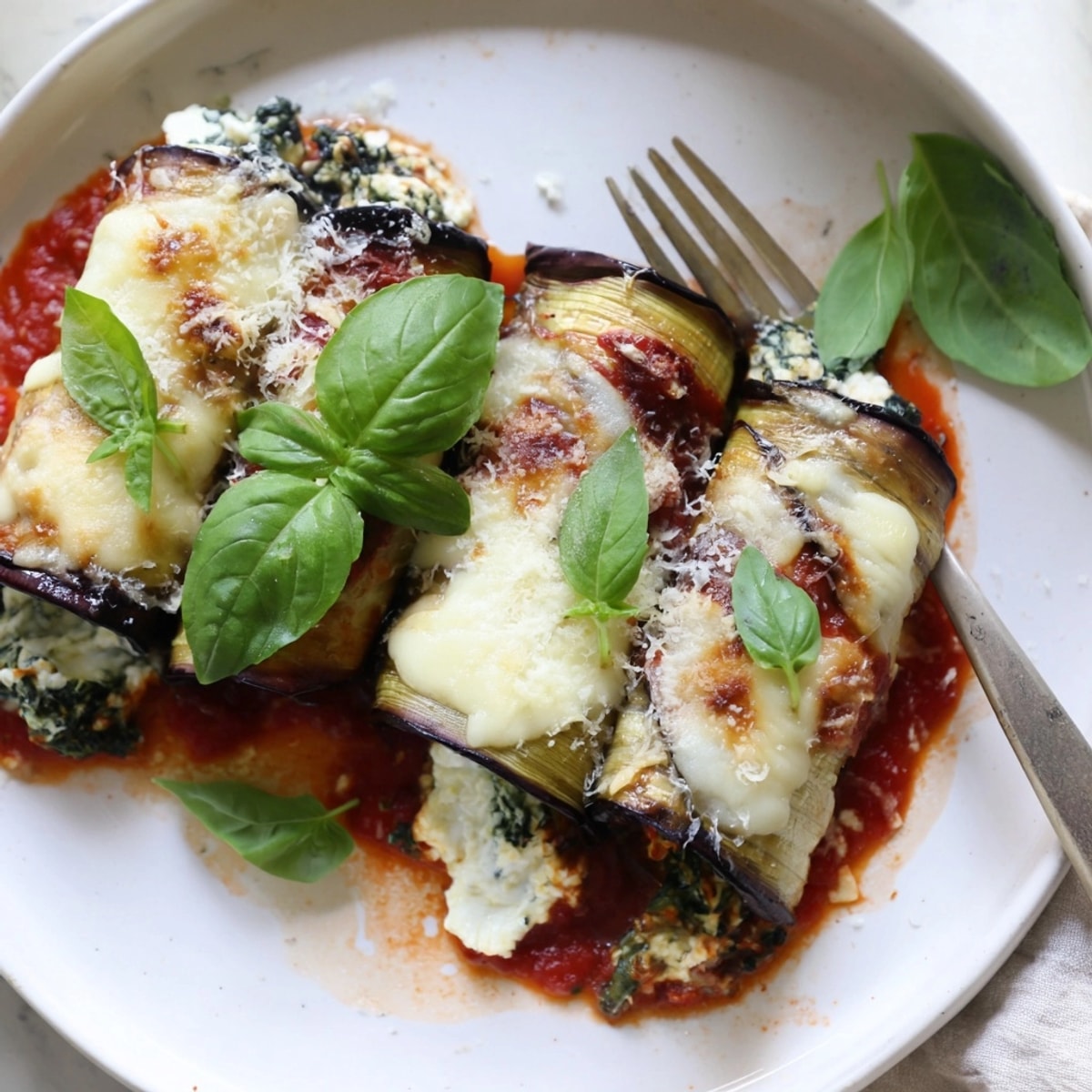 Close-up of homemade Eggplant Rollatini, showcasing crispy edges and a rich tomato sauce.