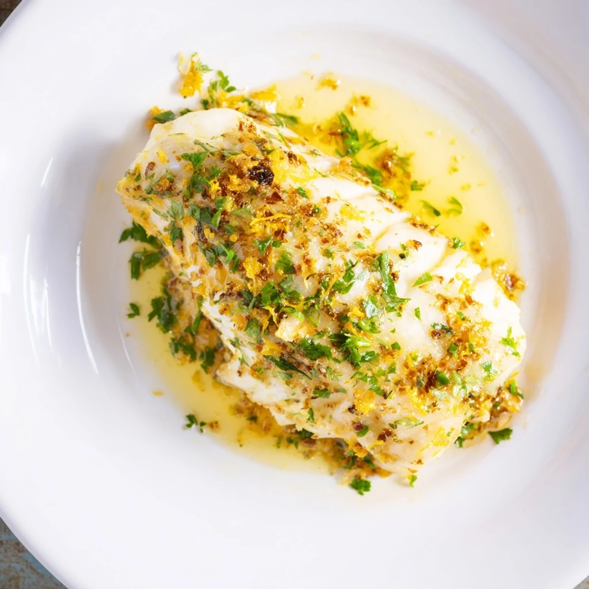 Flaky Baked Cod with Lemon Butter Sauce glistening, served alongside bright lemon wedges.