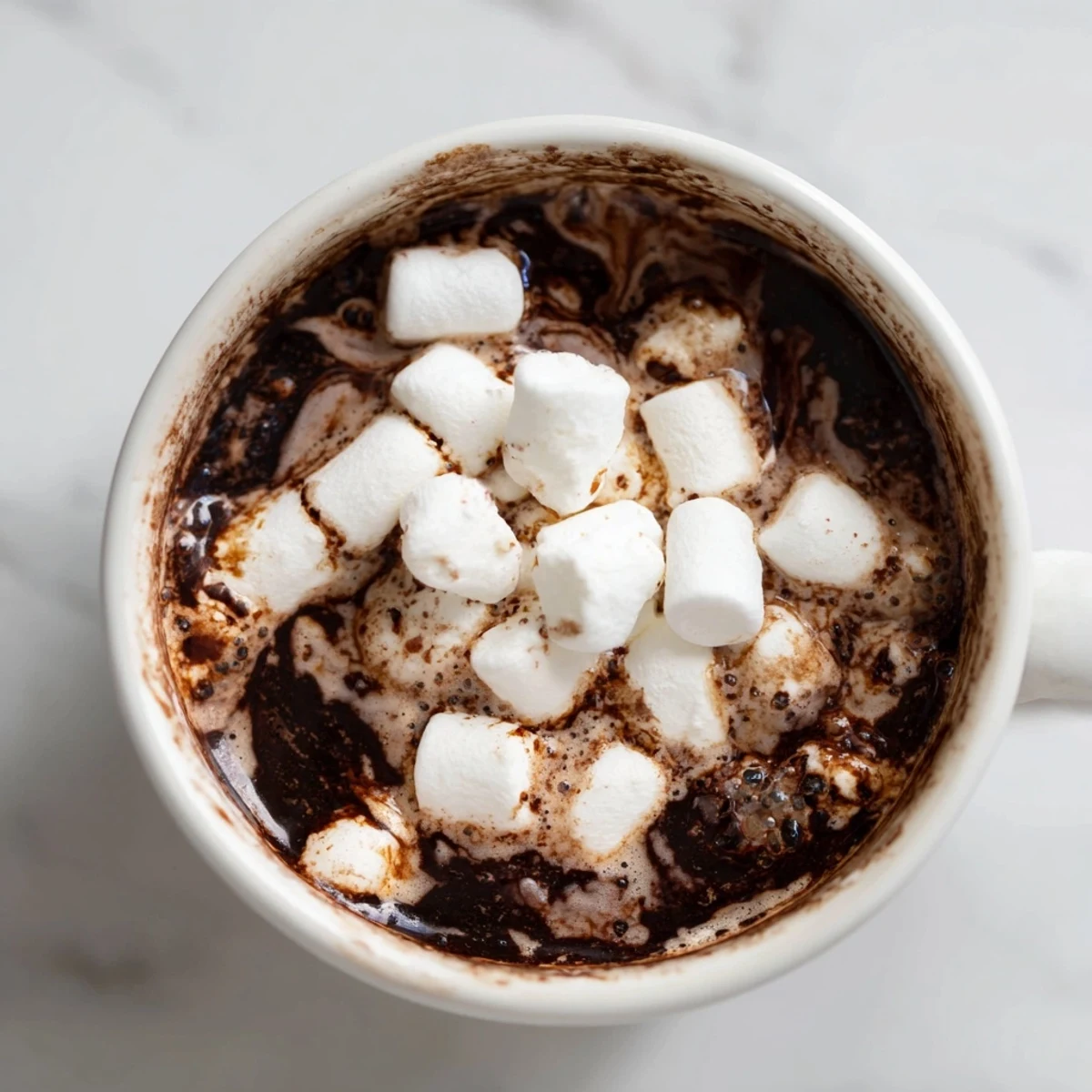 A mug of rich Spiced Hot Chocolate, topped with a cloud of marshmallows for a cozy treat.