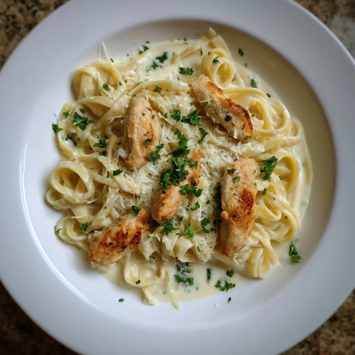 Steaming bowl of Chicken Alfredo, featuring Parmesan-coated fettuccine with chicken.