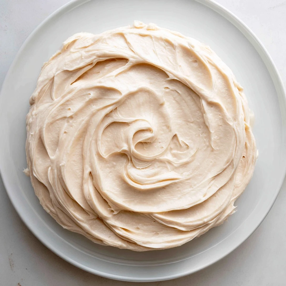 Fluffy, white buttercream frosting, perfect for decorating cakes and cupcakes with homemade charm.