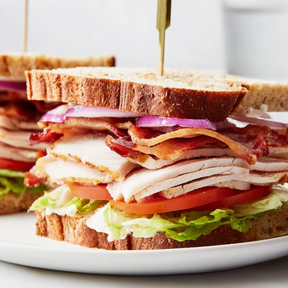 Golden-brown toasted bread cradles a delicious Turkey Club Sandwich with crispy turkey bacon and fresh vegetables.
