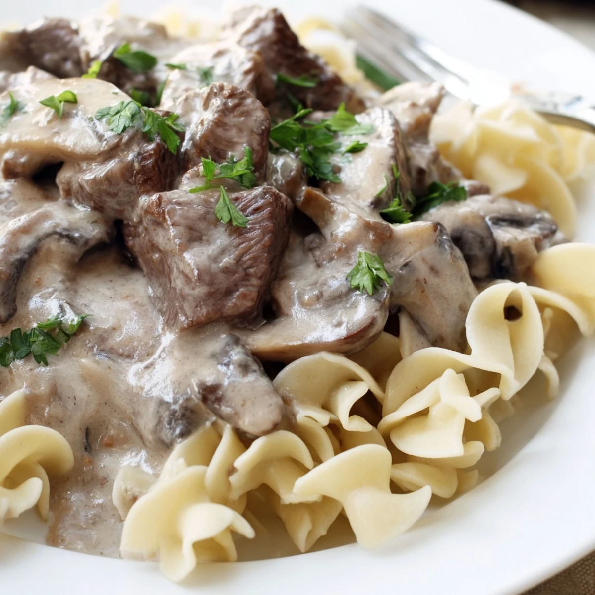 Hot Beef Stroganoff served over egg noodles with fresh parsley garnish for dinner.