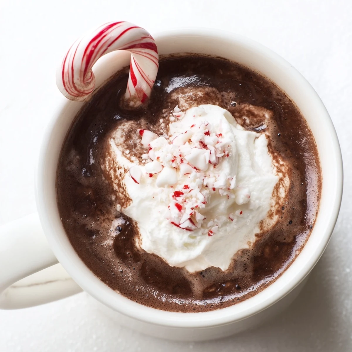 Rich peppermint stick hot cocoa in a festive mug, served with peppermint sticks and optional whipped cream.
