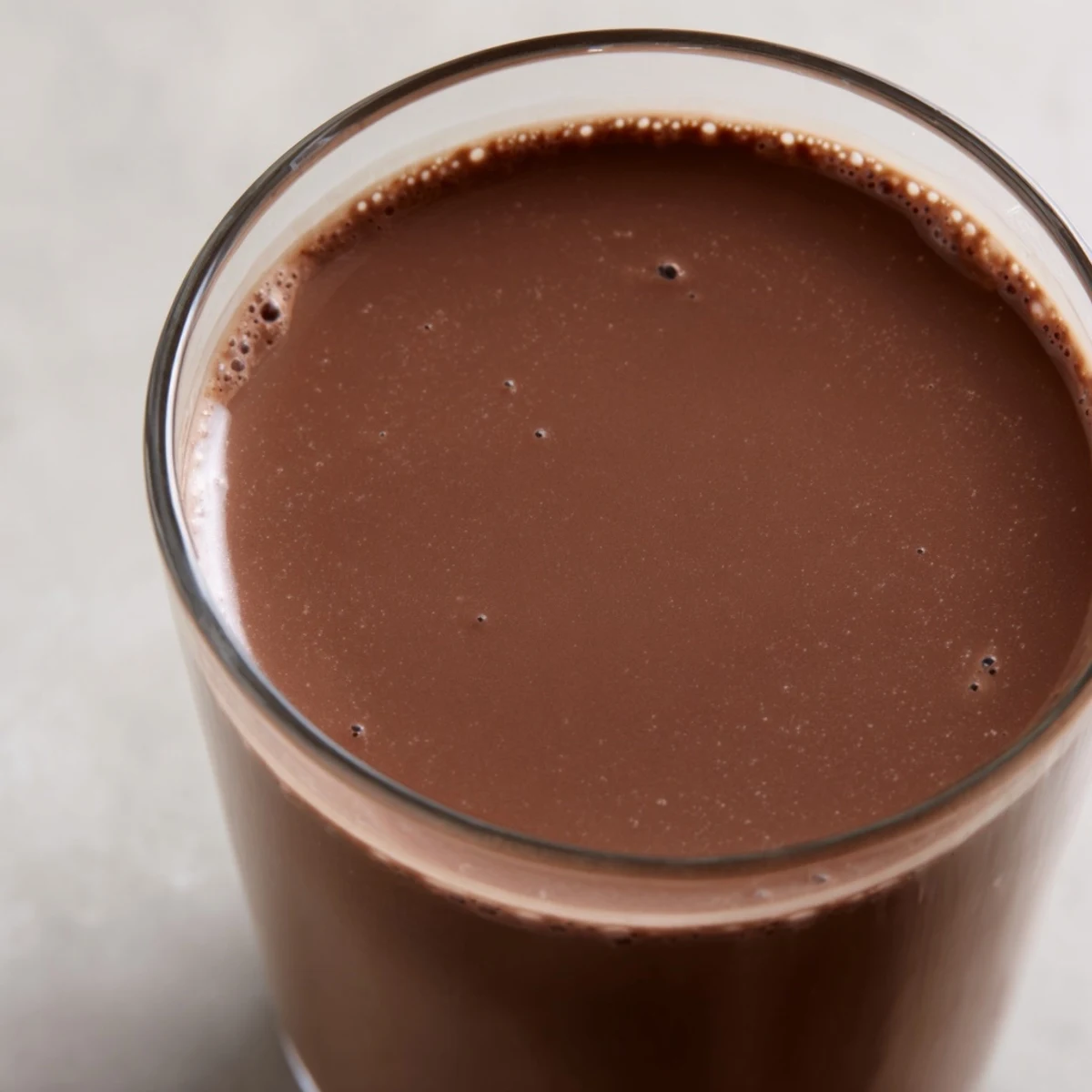 A chilled glass of homemade chocolate milk made with cocoa powder, sugar, and milk, garnished with a straw.