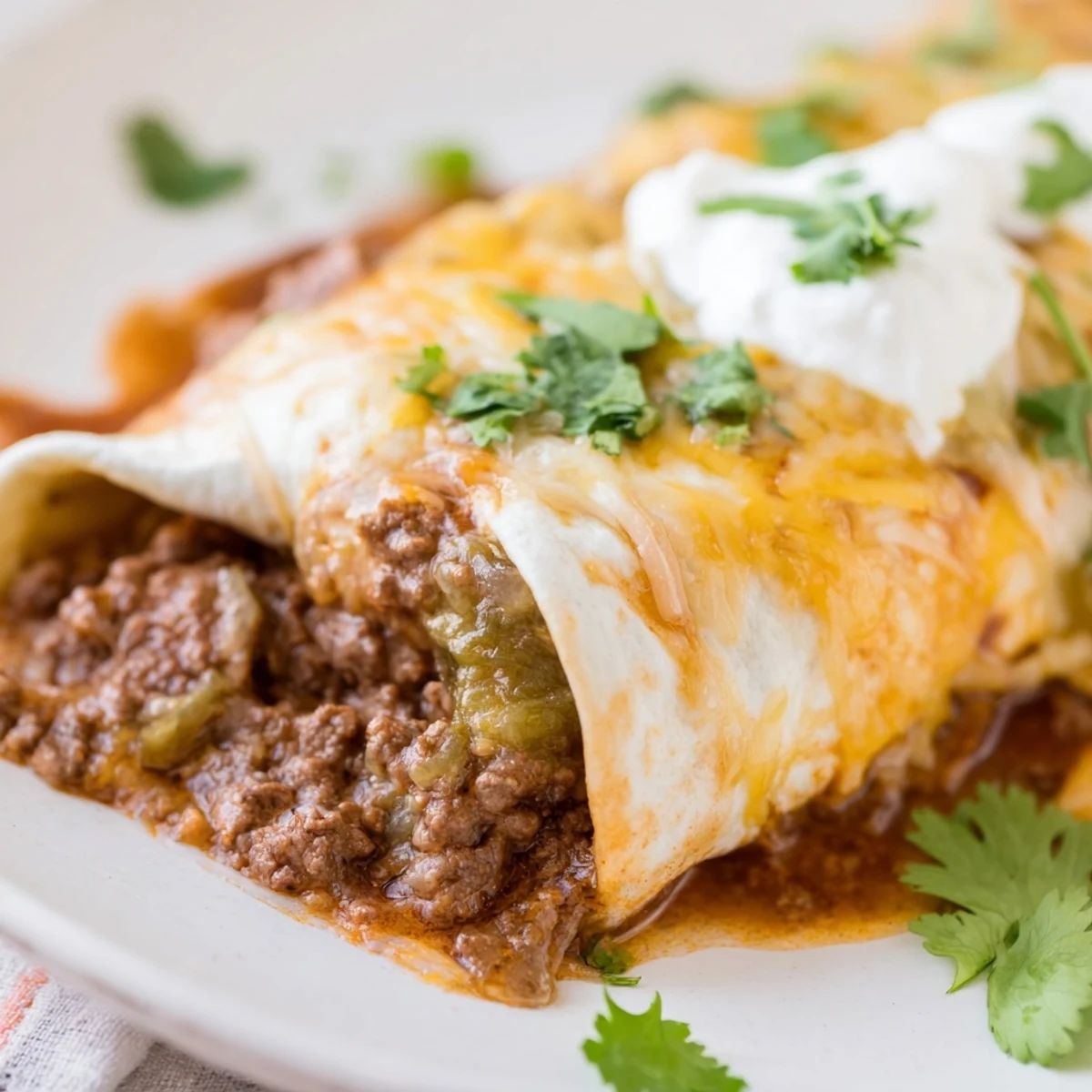 Beef Enchiladas with Green Chili Sauce baked with melted cheese and fresh cilantro garnish.