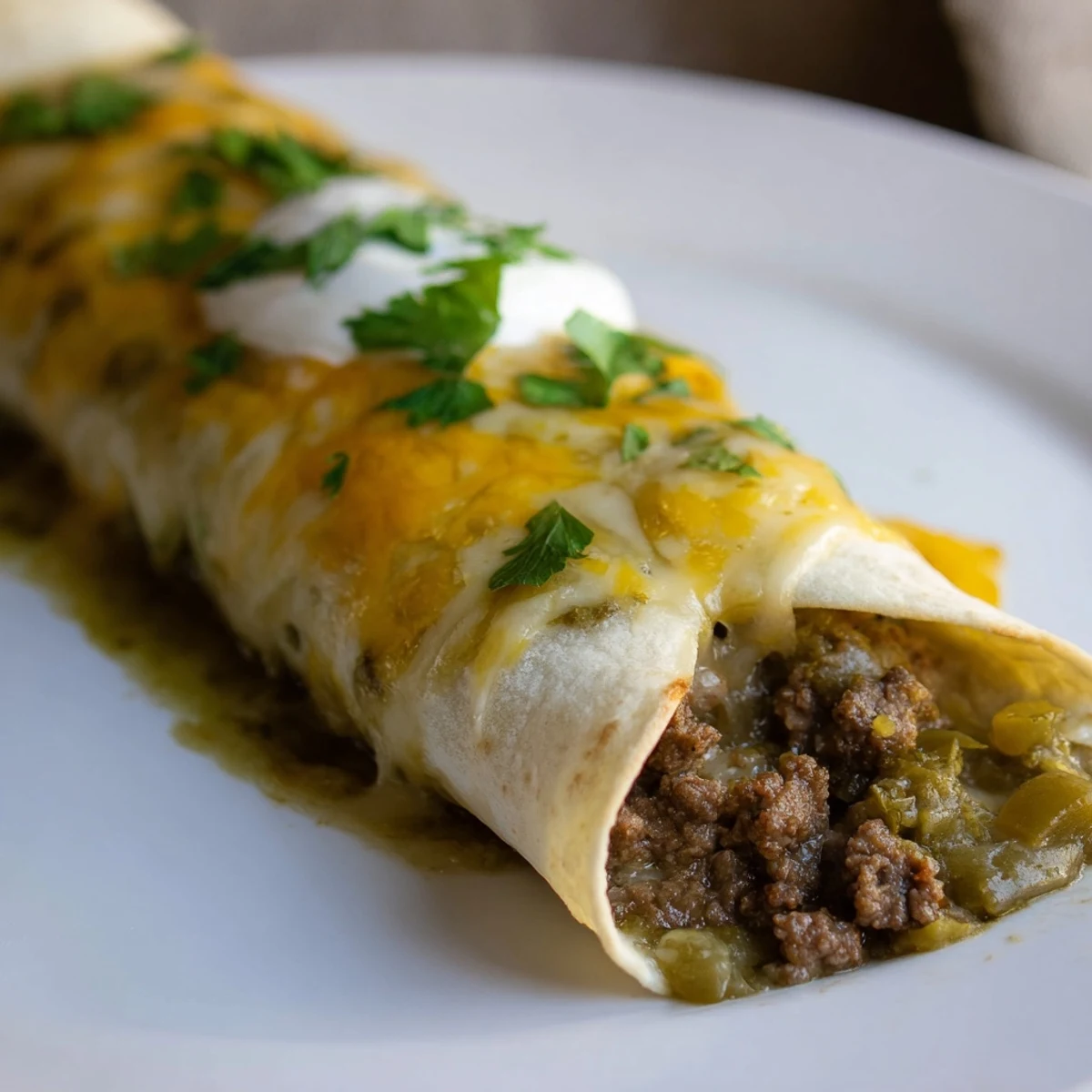 Ground beef filling inside Beef Enchiladas with Green Chili Sauce, smothered in vibrant green sauce.