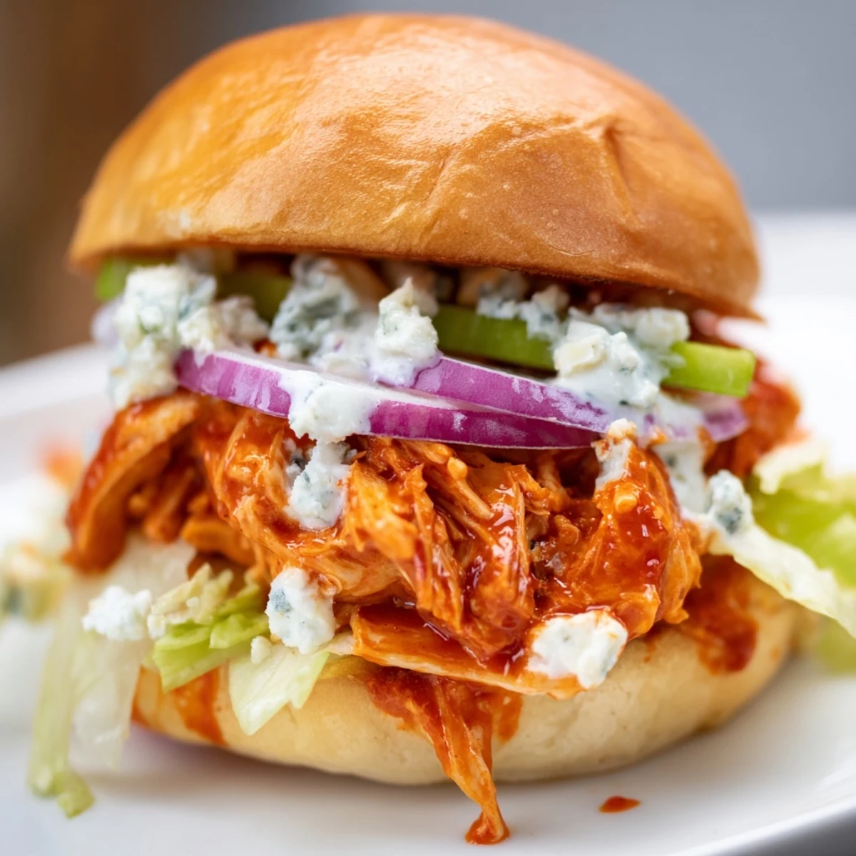 Game day favorite Spicy Buffalo Chicken Sliders with Blue Cheese, stacked with juicy chicken, crunchy veggies, and tangy sauce.