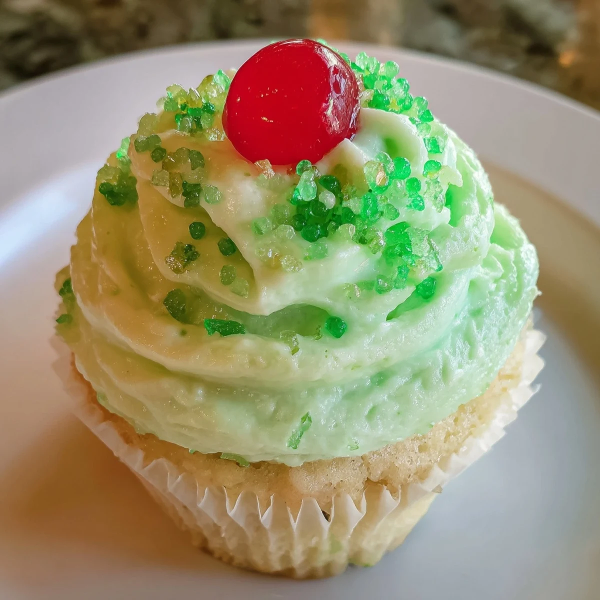 Freshly baked Shamrock Shake Cupcakes displayed on a cooling rack with vibrant green frosting and a dollop of cream.