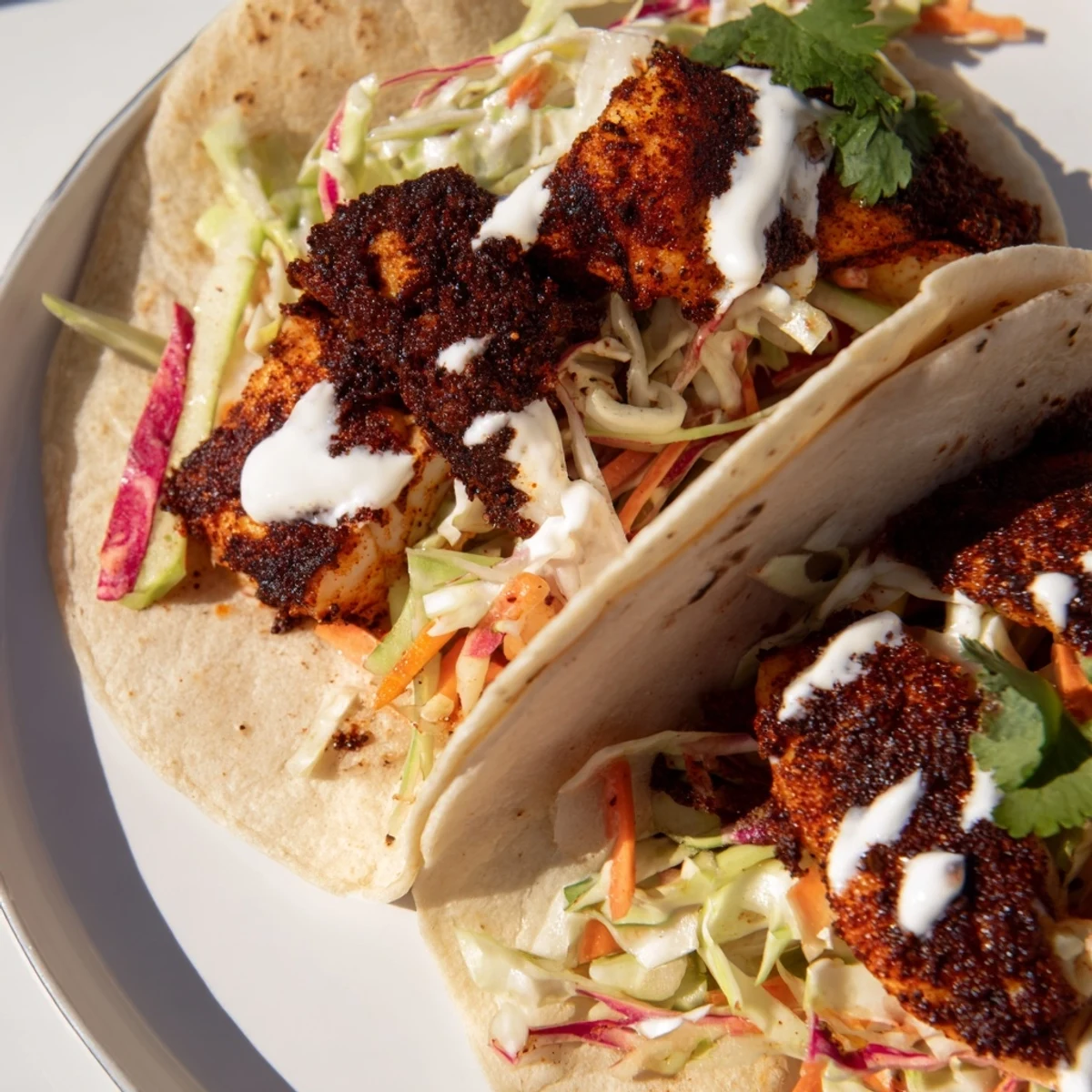Two Louisiana blackened fish tacos on a wooden board, garnished with fresh cilantro and lime wedges for a bright squeeze.
