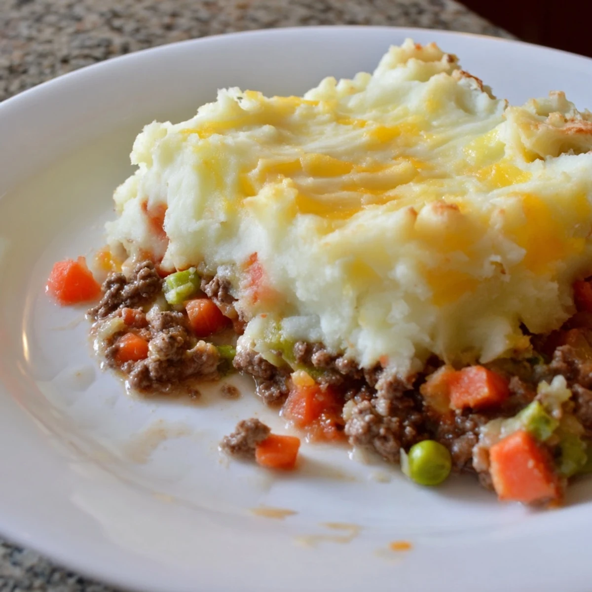 Golden baked Beef Shepherds Pie with Cheddar Mash bubbling in a dish, next to a rustic wooden serving spoon.