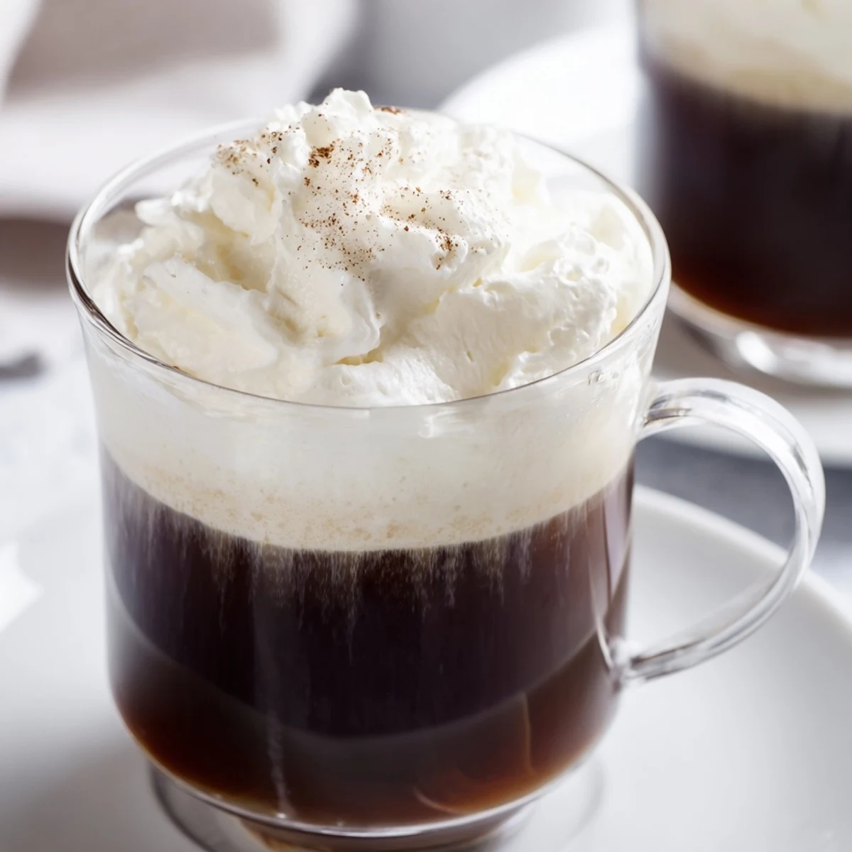 Two mugs of Irish Coffee Mocktail with Whipped Cream, cream floating over dark brew beside a sugar bowl.