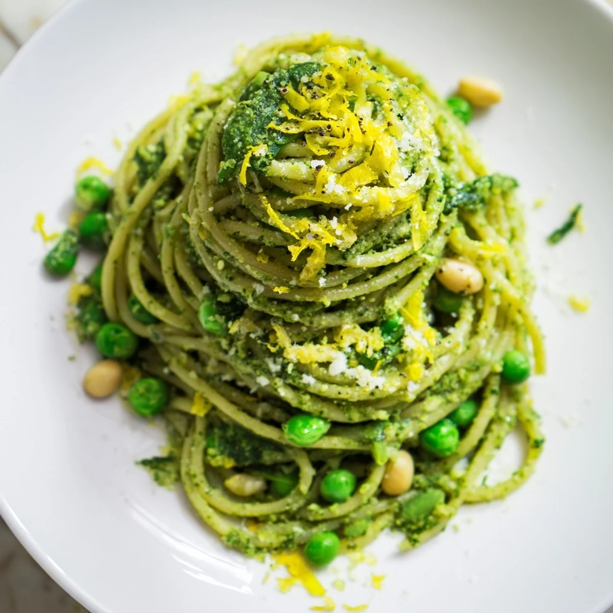 A steaming bowl of spring pea and mint pesto pasta garnished with lemon zest and Parmesan.