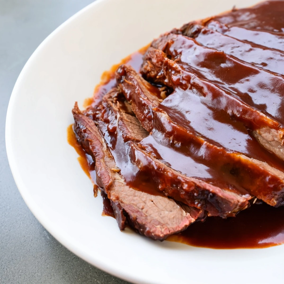 A close-up of slow cooked beef brisket with smoky BBQ sauce, served with tangy coleslaw and pickles.