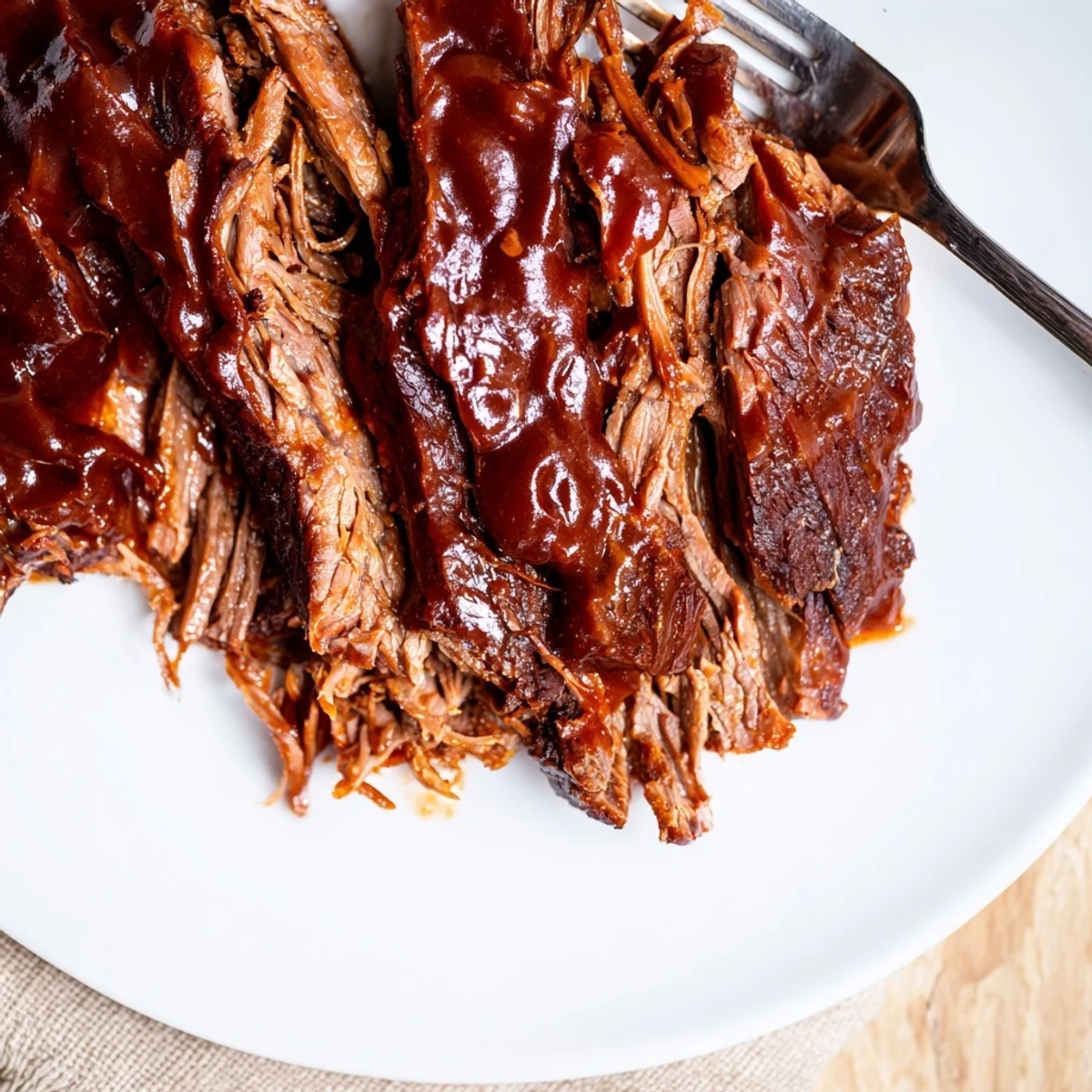 Slow Cooked Beef Brisket with BBQ Sauce sliced thick, smothered in a glossy, smoky barbecue sauce on a rustic platter.