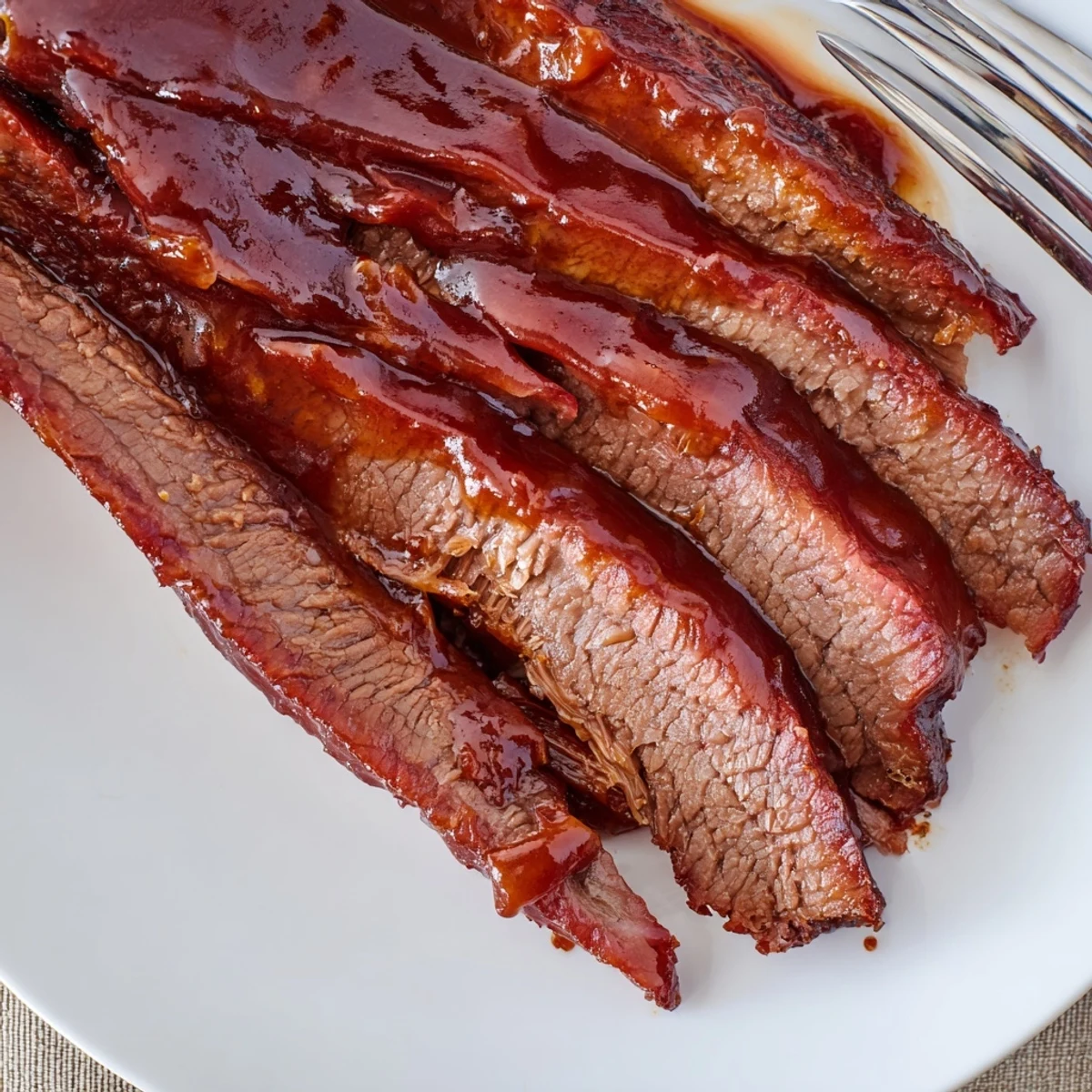 Close-up of Slow Cooked Beef Brisket with BBQ Sauce, showing a perfect smoke ring and rich, tangy sauce drips.