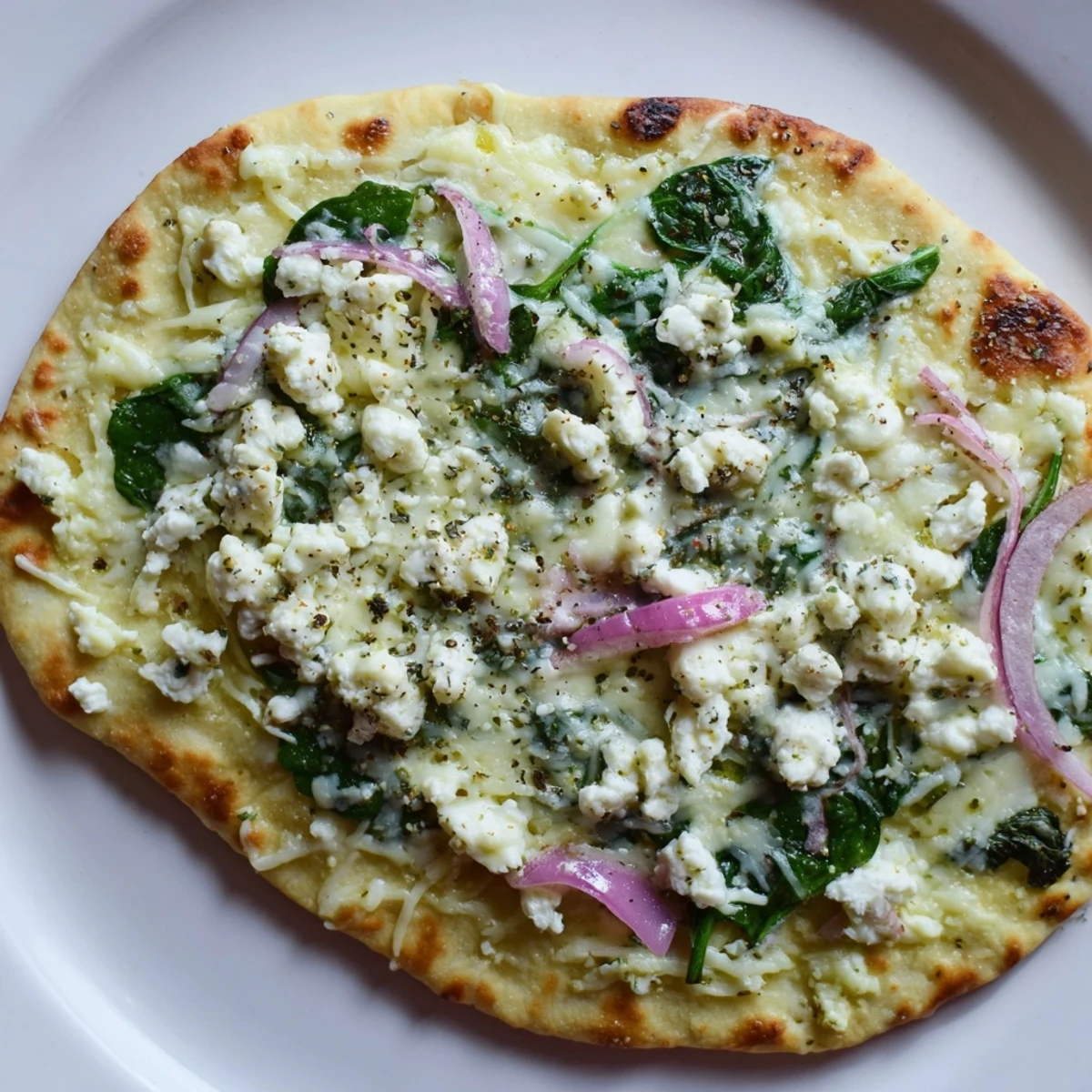 Golden, crisp flatbread pizza with melted mozzarella, fresh spinach, and creamy feta for a Mediterranean-inspired meal.
