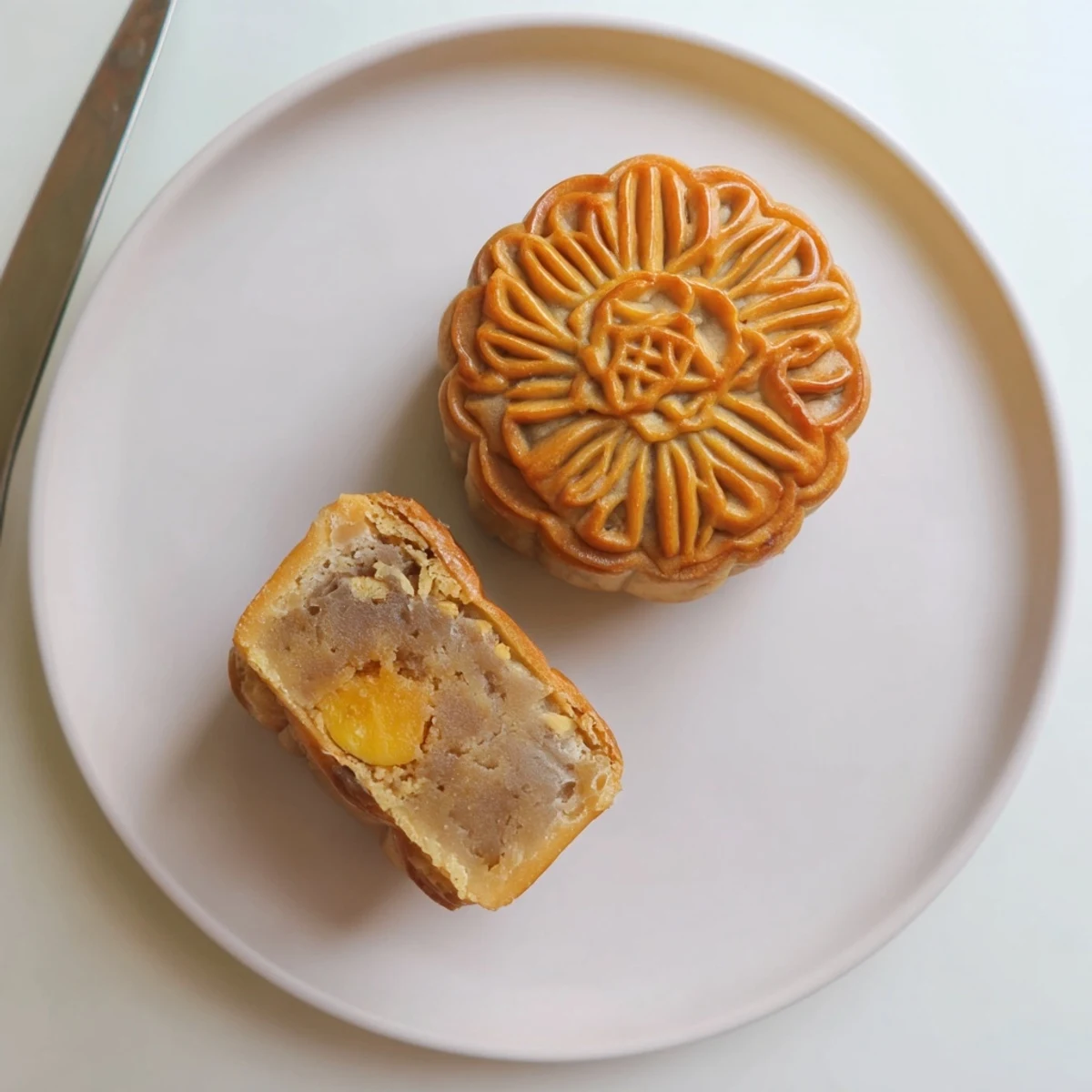 Golden-brown mooncakes, with intricate embossed patterns, rest on a parchment-lined tray, showcasing their tender pastry and sweet lotus seed filling.