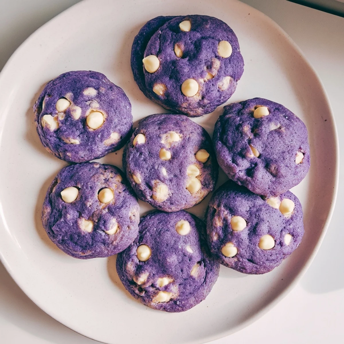 A close-up shot of a White Chocolate Ube Cookie broken open to reveal its tender, purple interior and gooey white chocolate chunks.