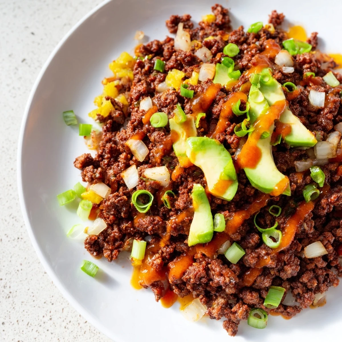 Savory ground beef and roasted veggies topped with hot honey drizzle in a meal prep bowl.