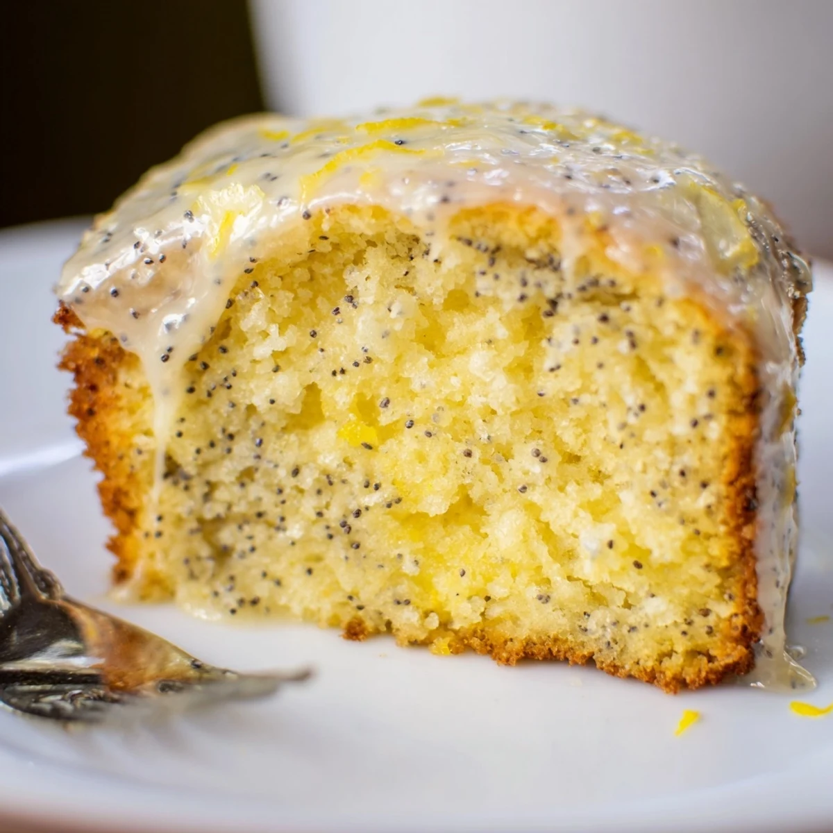 Freshly baked Lemon Poppy Seed Cake glistening with a sweet lemon glaze, ready for an afternoon treat.
