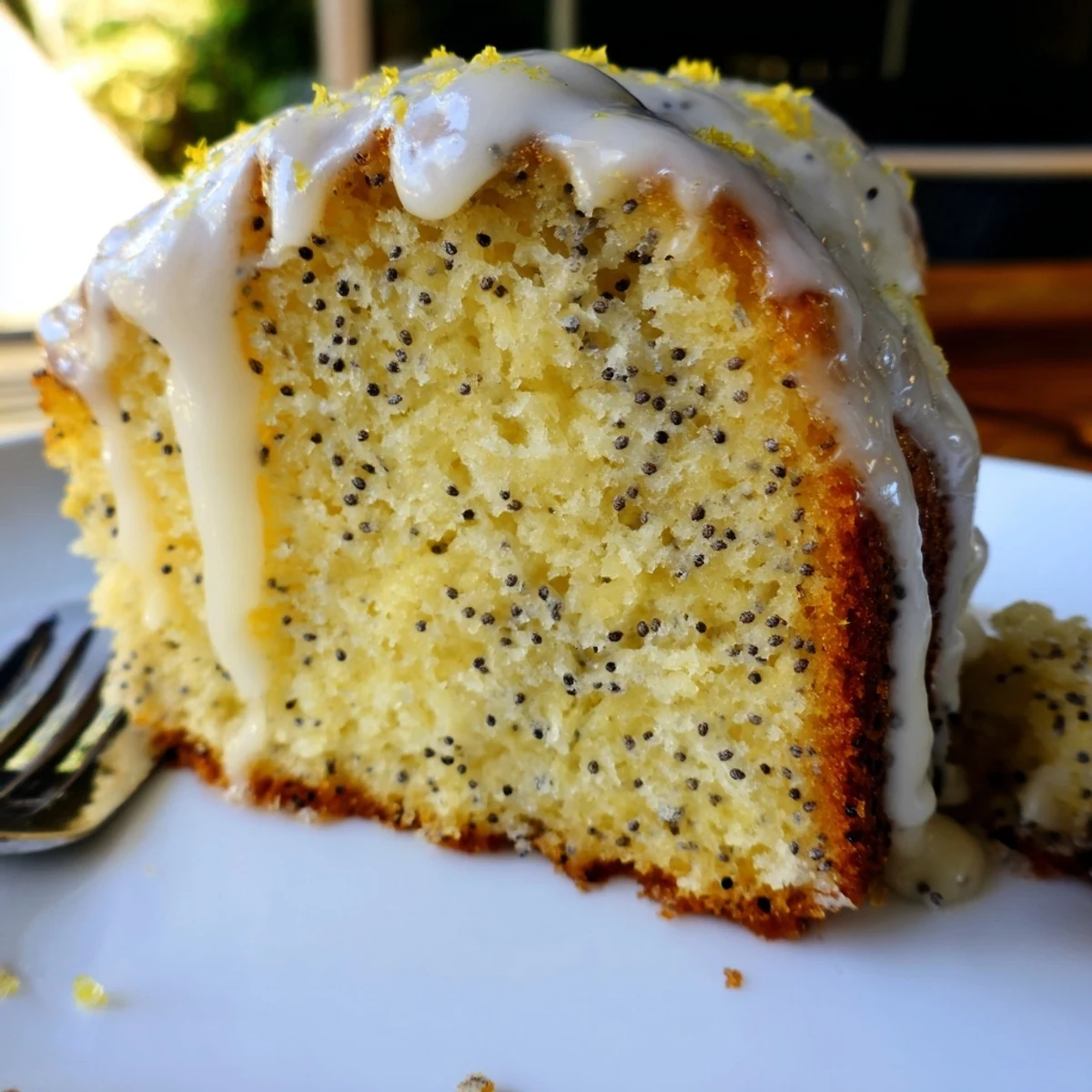 A slice of moist Lemon Poppy Seed Cake reveals a tender crumb flecked with poppy seeds.