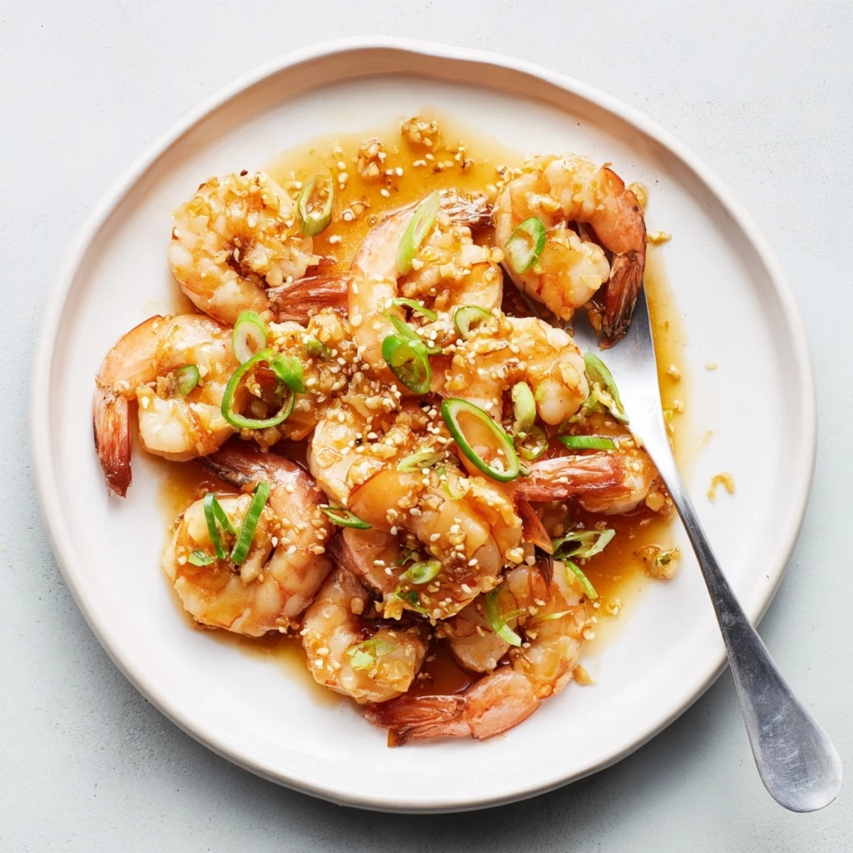 Close-up of High Protein Honey Garlic Shrimp garnished with fresh green onions and sesame seeds.