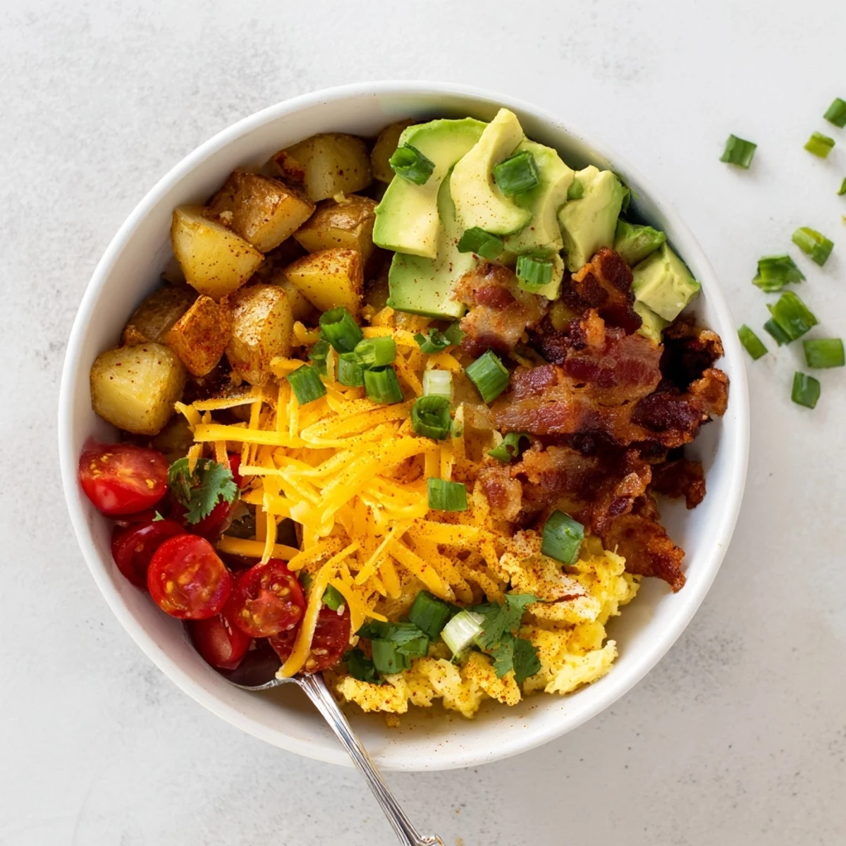 A close-up of a hearty Loaded Breakfast Bowl with fluffy scrambled eggs and crispy roasted potatoes.