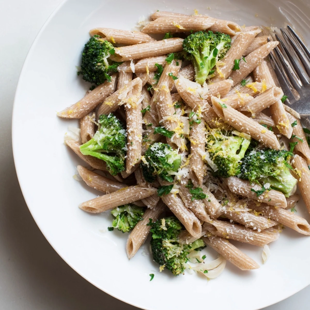 Top-down view of a pan of Easy Healthy Broccoli Pasta featuring al dente penne tossed with garlic, red pepper flakes, and a savory olive oil lemon sauce.