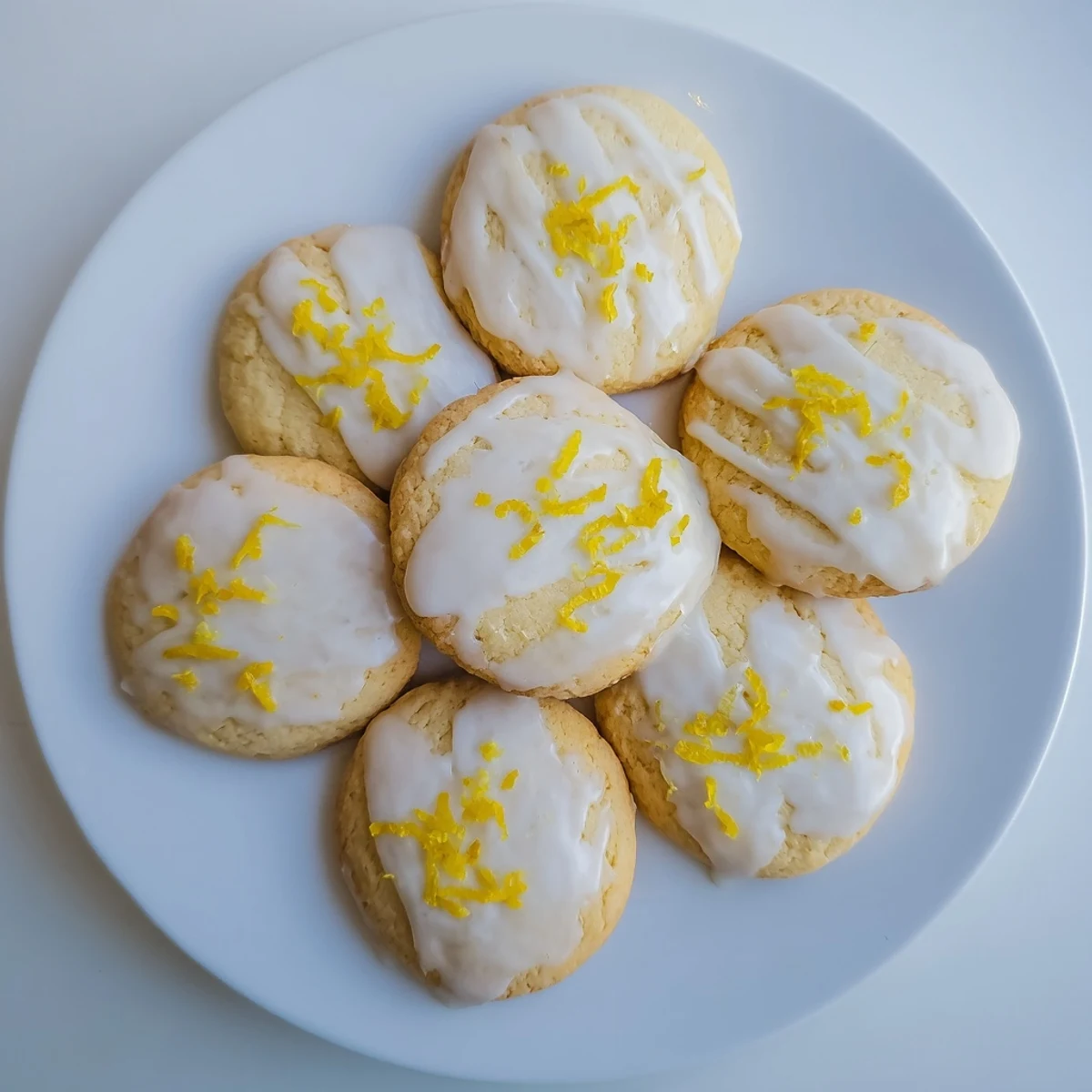 Golden-baked Limoncello cookies rest on a cooling rack with a shiny lemon glaze and fresh zest garnish, perfect for spring gatherings.