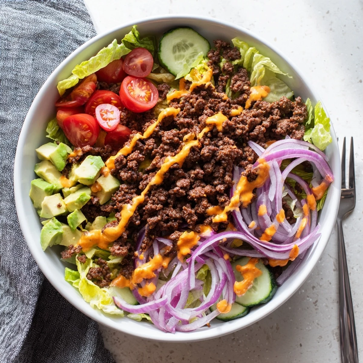 Colorful gluten free Burger Bowl featuring seasoned beef, melted cheese, and fresh veggies served in a white ceramic bowl.