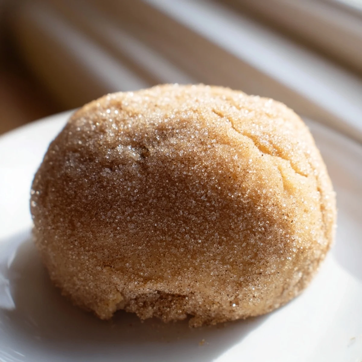Golden caramel apple pie bombs with cinnamon sugar coating on a white baking sheet