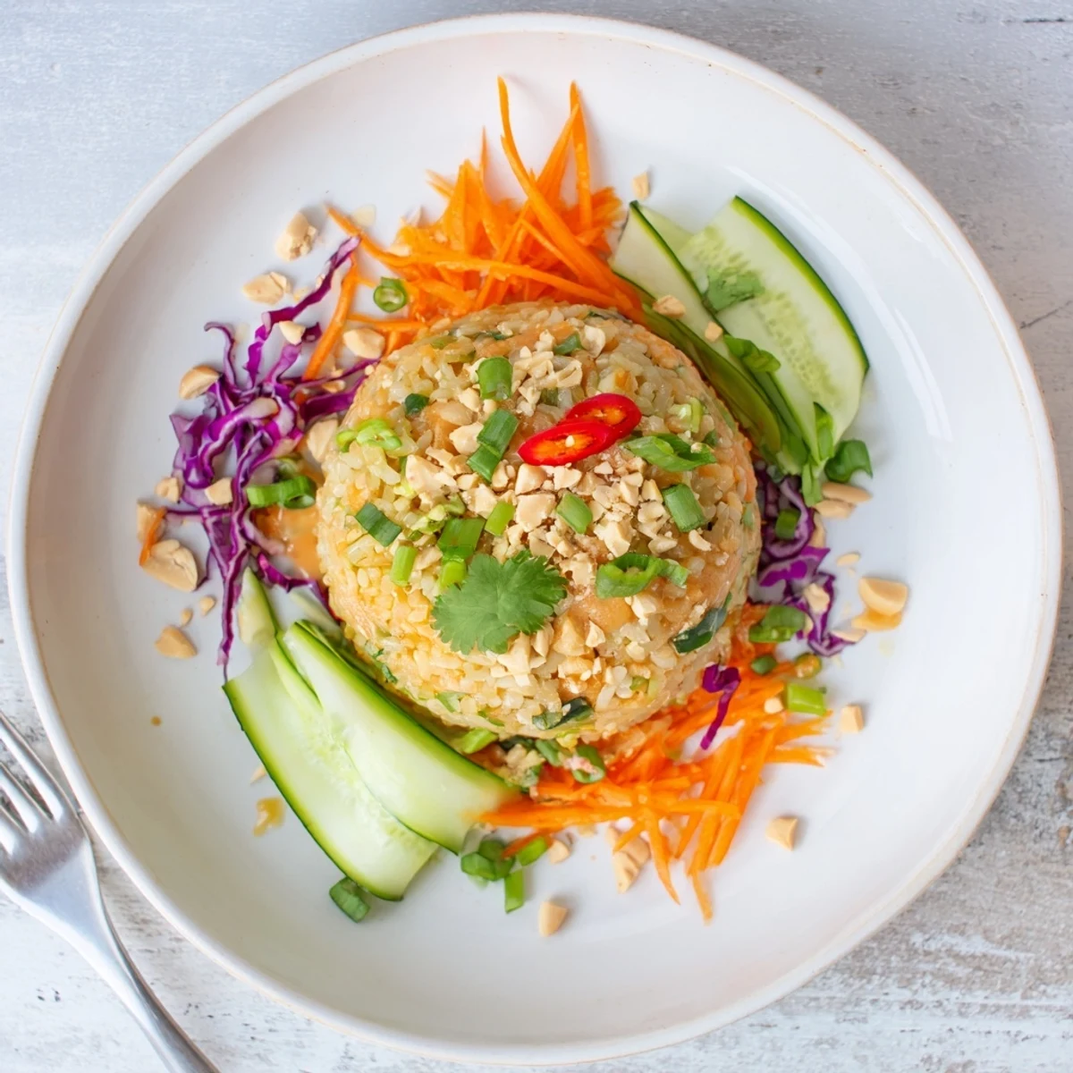 Golden fried rice salad topped with fresh cilantro, peanuts, and tangy peanut sesame sauce