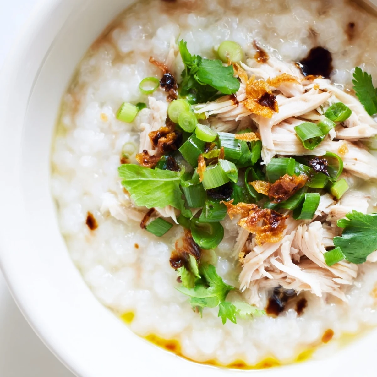 Steaming bowl of savory rice porridge featuring shredded holiday turkey meat with ginger, garlic, and sesame oil drizzle