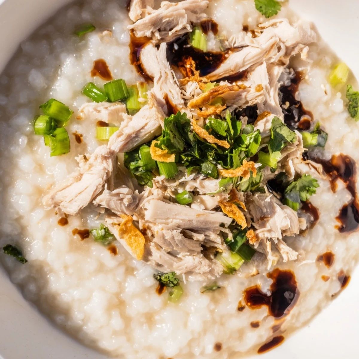 Comforting Asian-inspired turkey congee simmered to creamy perfection with aromatic broth and vibrant green garnish toppings