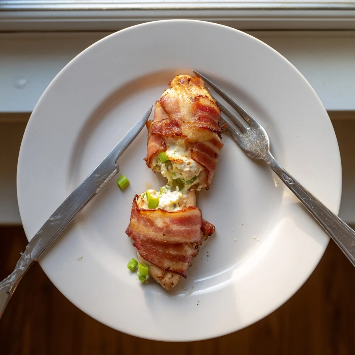 Juicy stuffed chicken breast wrapped in bacon revealing jalapeño cheese center on serving dish
