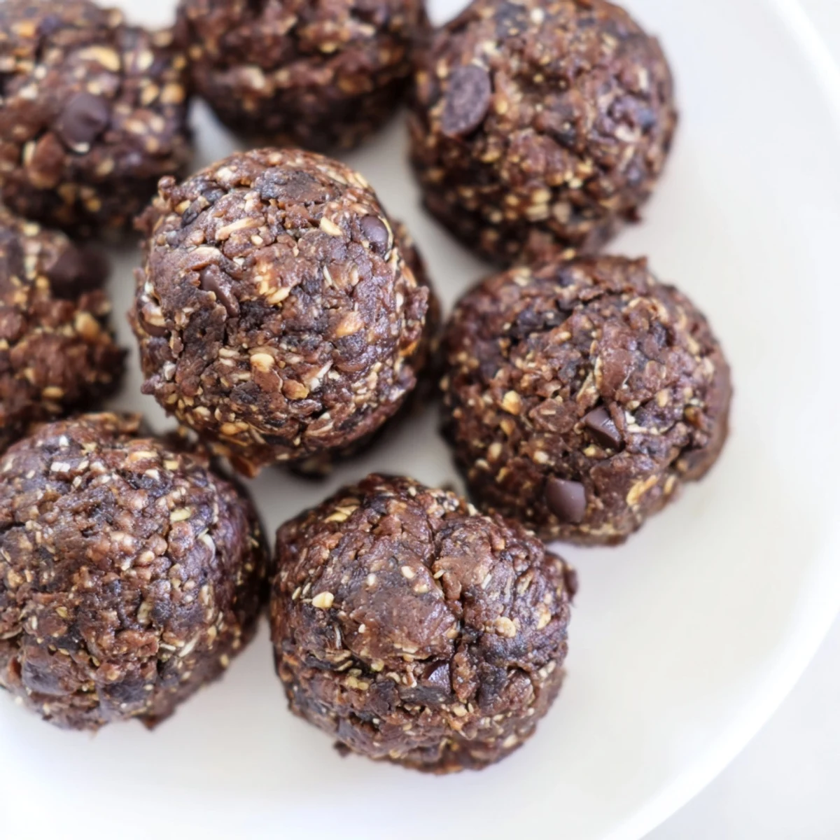 Bite-sized no bake protein balls featuring creamy peanut butter and dark chocolate chunks on parchment paper