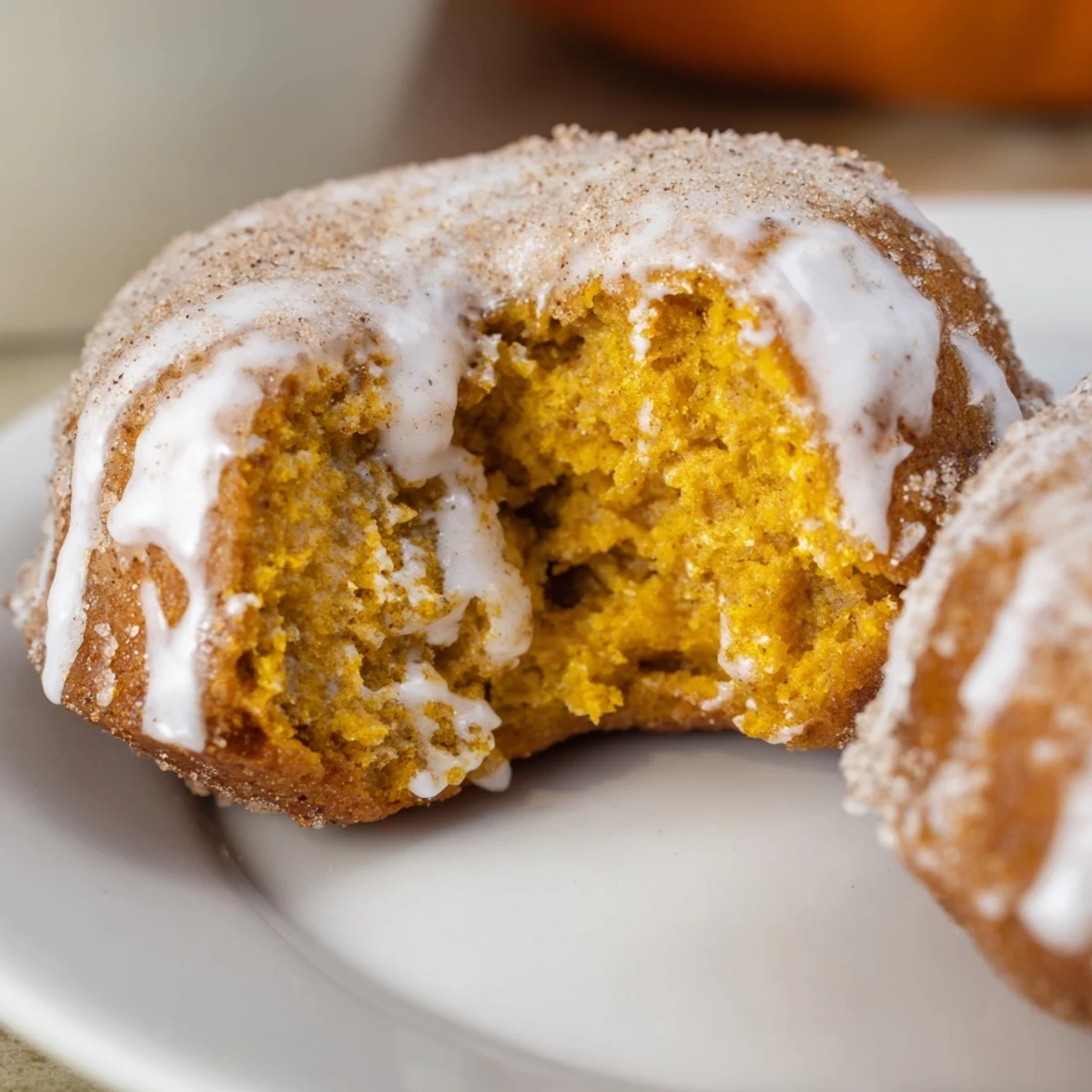 Golden brown pumpkin spice biscuit donuts coated in cinnamon sugar with sweet vanilla glaze drizzle