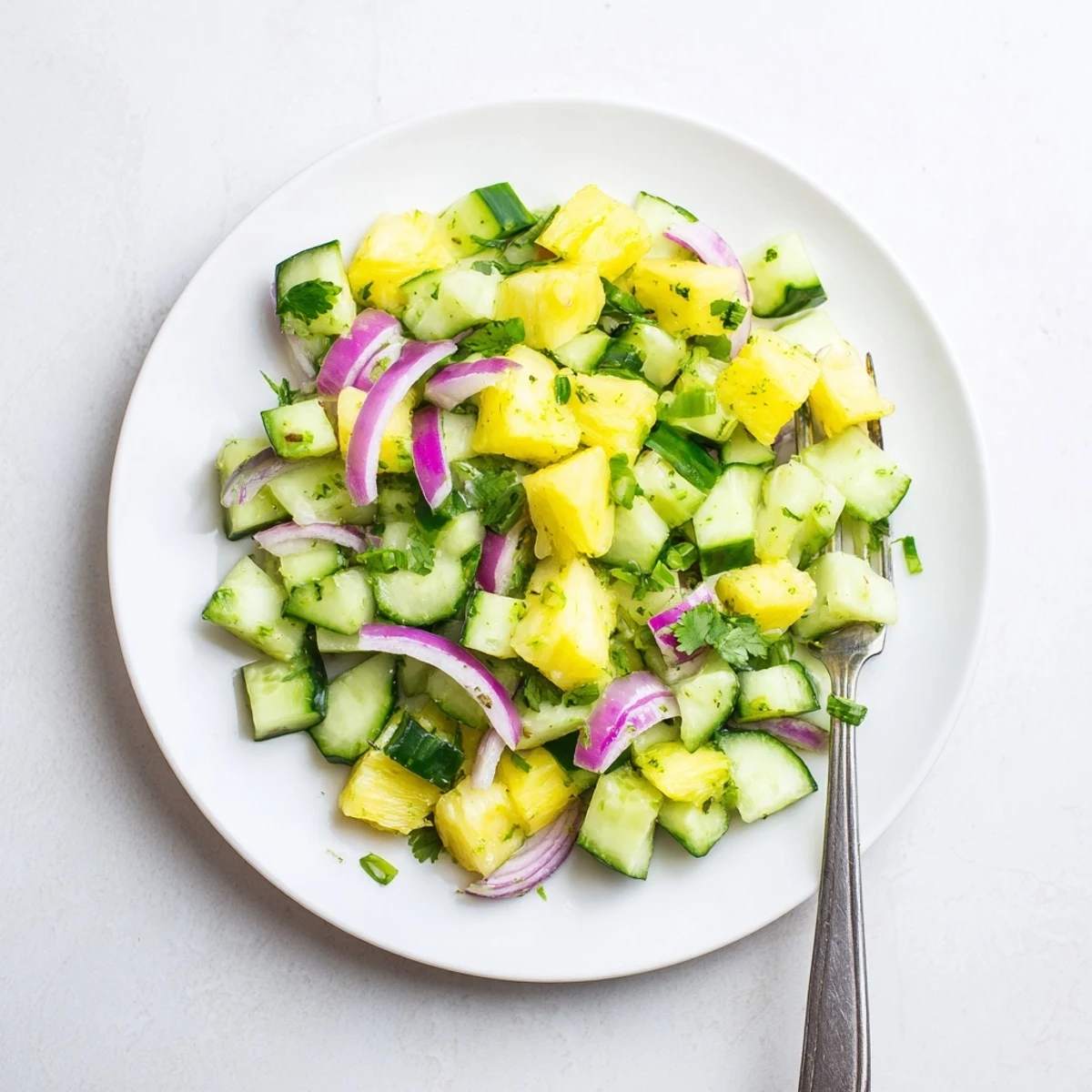 Tropical pineapple cucumber salad plated with lime wedges and drizzled with tangy vinaigrette