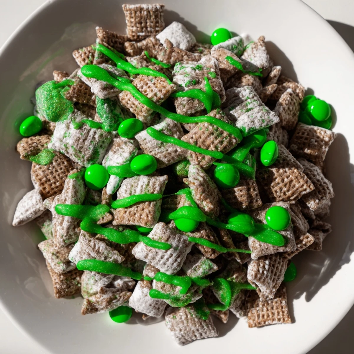 Festive St. Patricks Day puppy chow coated in melted chocolate peanut butter and dusted with powdered sugar