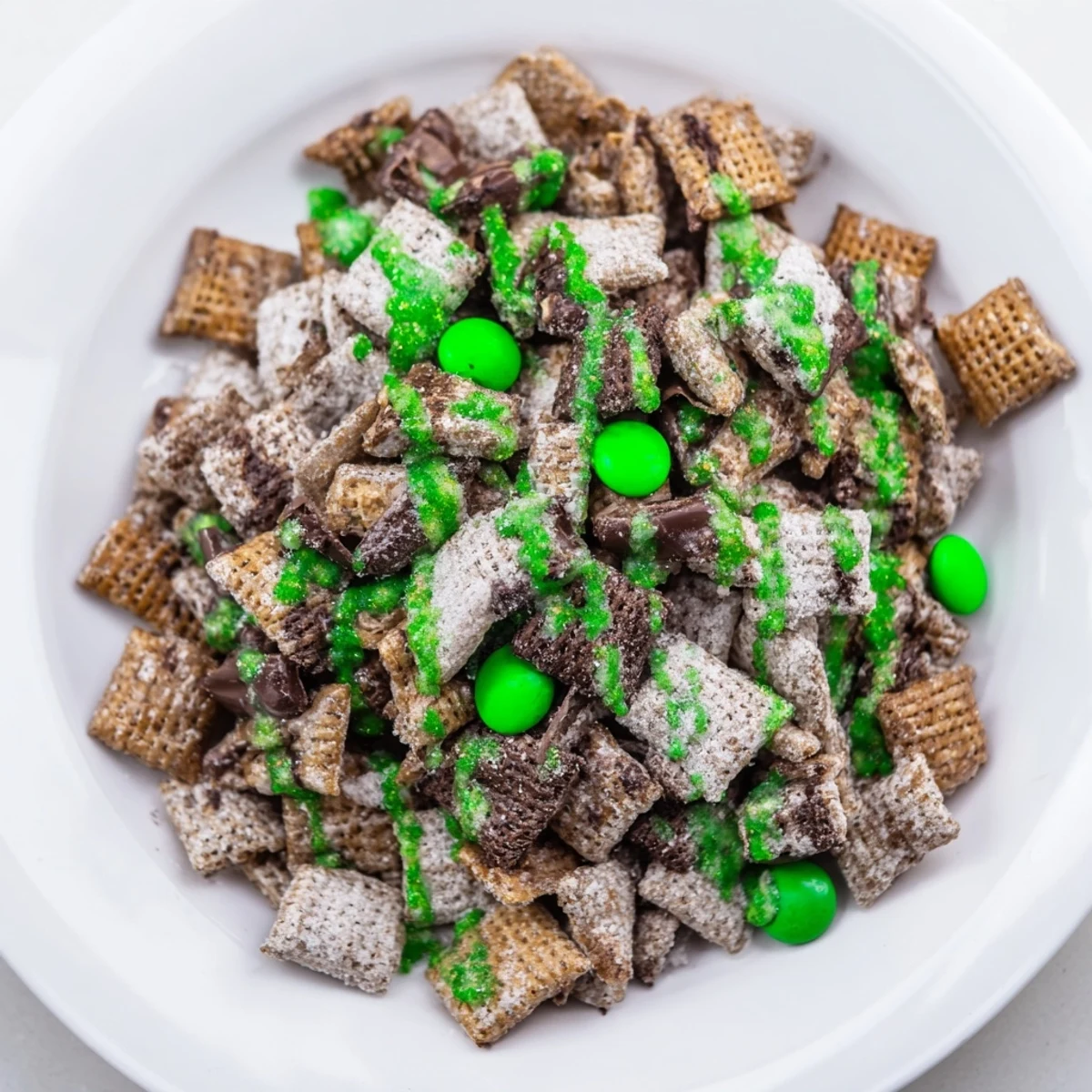 Crunchy chocolate peanut butter St. Patricks Day puppy chow served in a bowl with vibrant green decorations