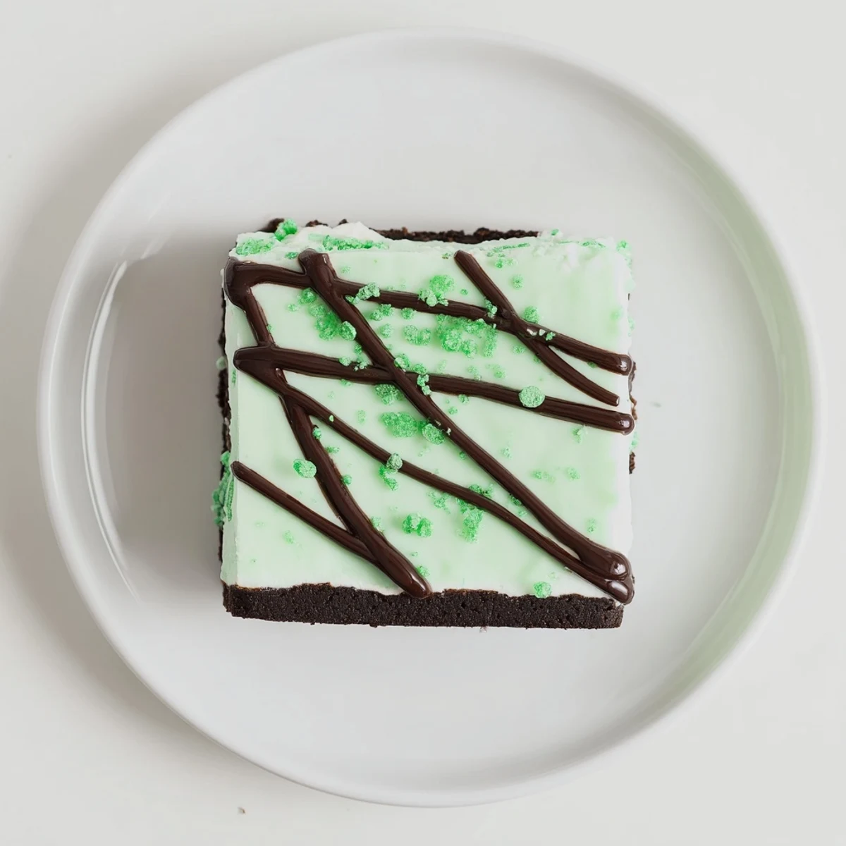 Creamy white chocolate mint cheesecake fudge bars layered over rich chocolate cookie crust topped with festive green sprinkles