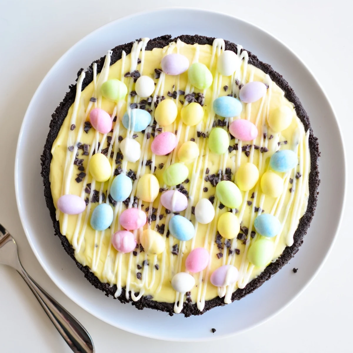 Velvety smooth Easter Egg Cheesecake drizzled with white chocolate and topped with festive colorful eggs