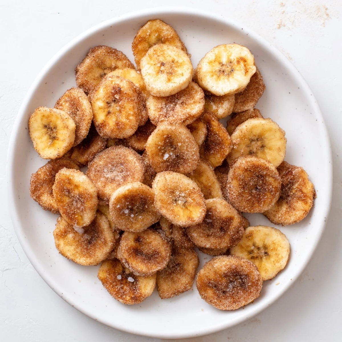 Crispy baked banana chips coated with warm cinnamon sugar cooling on wire rack