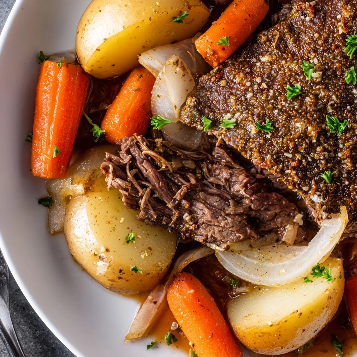 Hearty slow cooker steak and potatoes featuring seared beef, buttery carrots, and onions in a rich beef broth with herbs