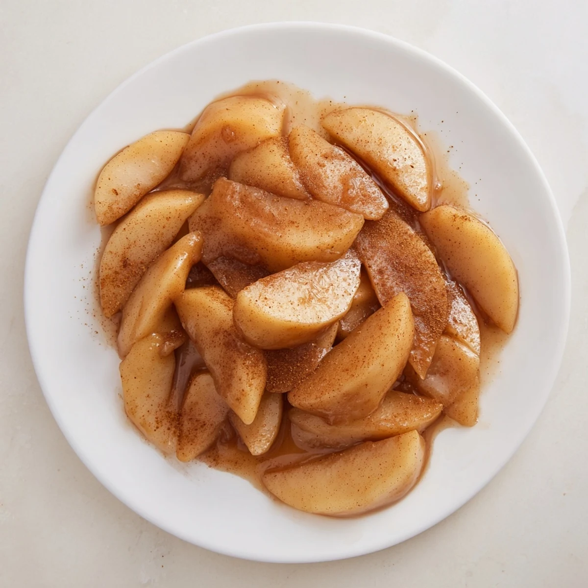 Golden tender apple slices coated in warm cinnamon brown sugar syrup drizzled over vanilla ice cream
