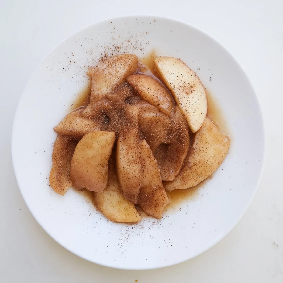 Steaming Instant Pot cinnamon apples served in white bowl with melted butter and maple cinnamon glaze