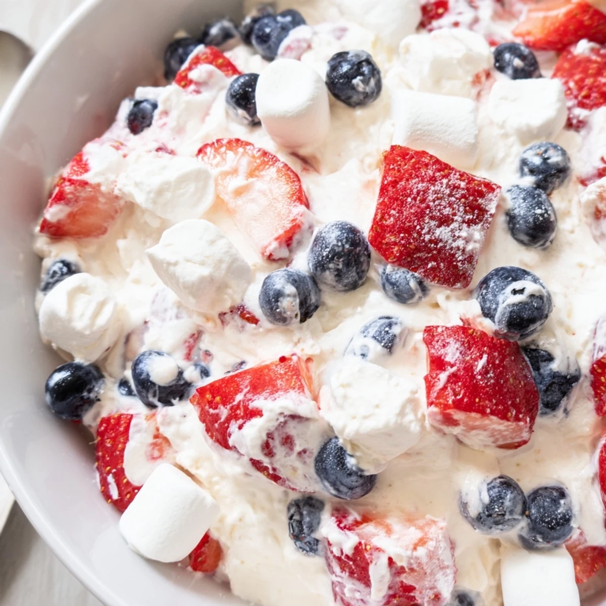 Red white blue cheesecake salad served chilled in a bowl with juicy strawberries