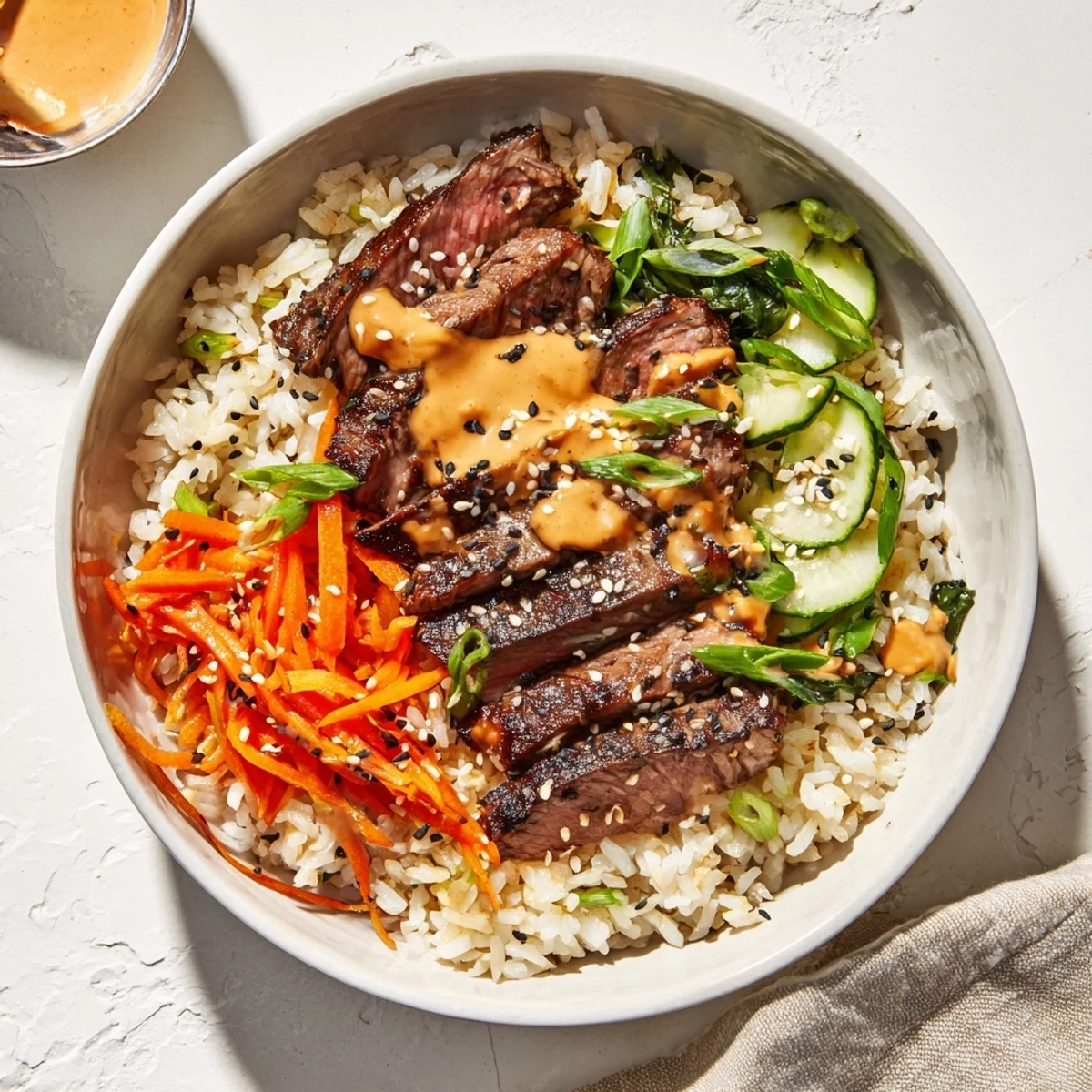 Sizzling marinated steak over fluffy rice drizzled with spicy cream sauce in Korean BBQ steak rice bowls