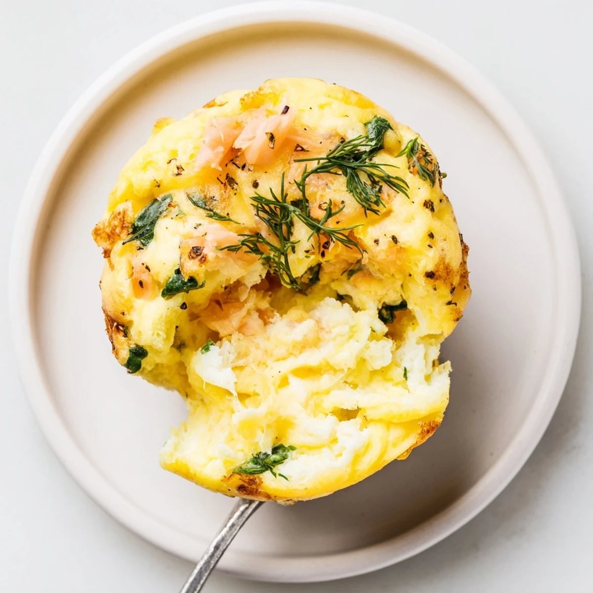 Plated Smoked Salmon Egg Muffins with golden tops, fluffy centers, fresh dill.